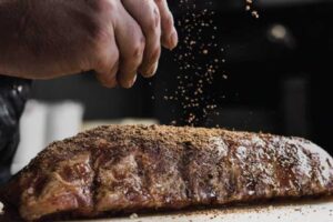 sprinkling seasoning on beef